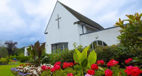 Gwent Crematorium building surrounded by bright flowers / Adeilad Amlosgfa Gwent wedi'i amgylchynu gan flodau llach.ar