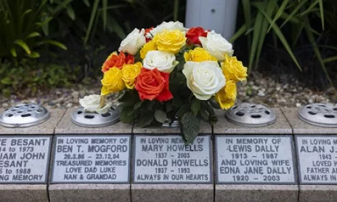 A memorial vase with a plaque and flowers / -Fâs goffa gyda phlac a blodau.